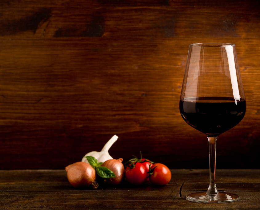 Una copa de vino al lado de unas verduras